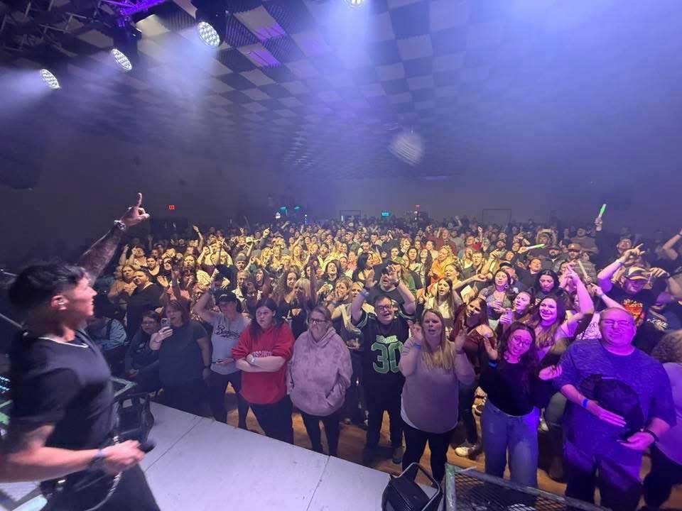 Ryders Roadhouse in Wisconsin Rapids Wisconsin A musician performs onstage for a large, cheering crowd in a lively concert venue.