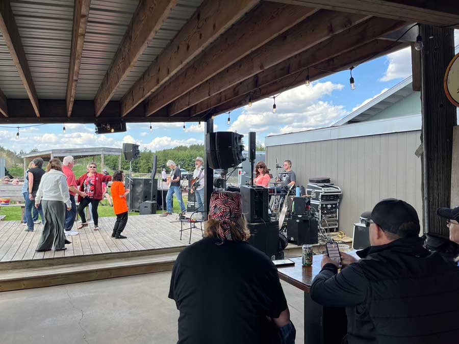 Ryders Roadhouse in Wisconsin Rapids Wisconsin People watching a band perform while others dance outside on a sunny day under a covered patio.